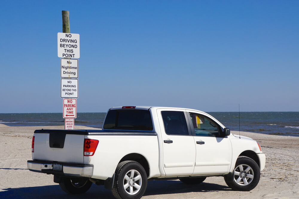 SUV parked beside a beach regulations post