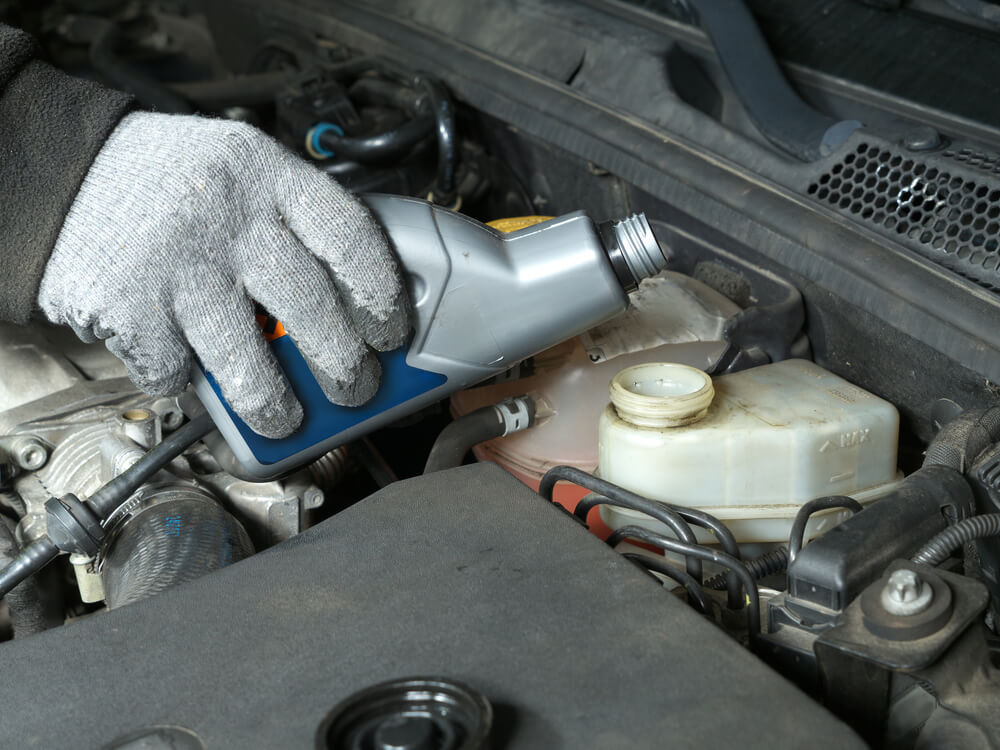 Auto mechanic topping up brake fluid in a vehicle