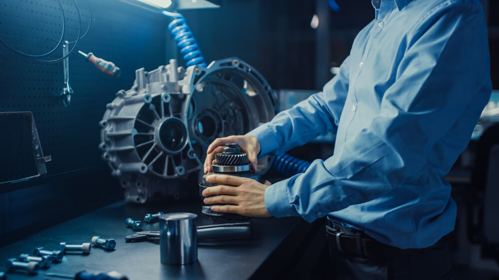 mechanic holding a gear at a service center. - luxury cars bad mileage