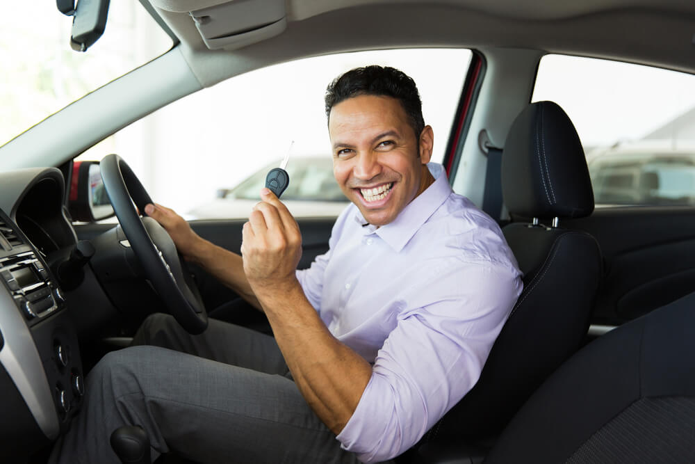 handsome middle aged man showing a car key inside his new vehicle - Why Sedans depreciate quickly