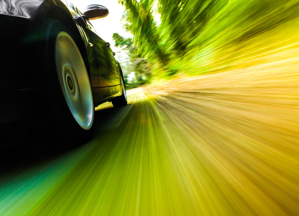 side view of wheels of a car going too fast, motion blur. - luxury cars bad mileage